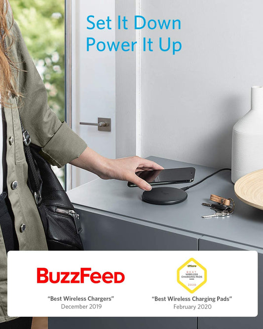 Person using a wireless charging pad with a smartphone, featuring BuzzFeed awards on a blurred background.